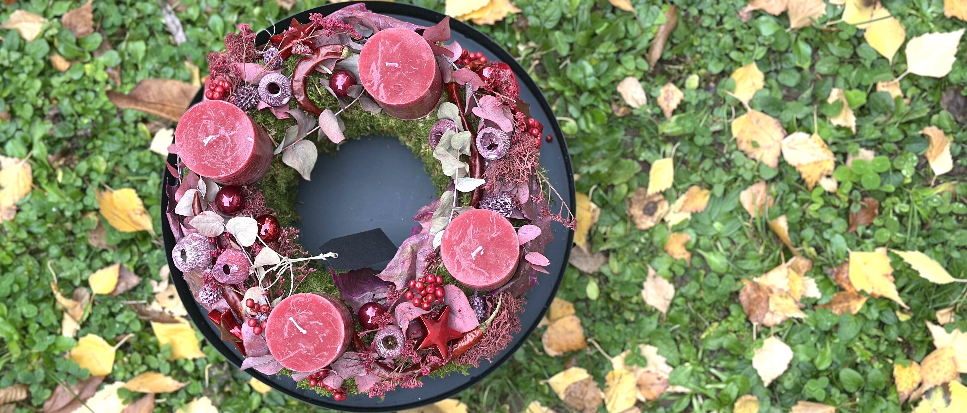 Adventskranz mit roten Kerzen auf Gras